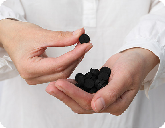 доктор держит упаковку активированного угля и смотрит на пациента